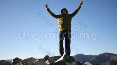 一个年轻人站在山顶上，享受着周围的自由和美丽。 慢动作，1920x1080，全高清